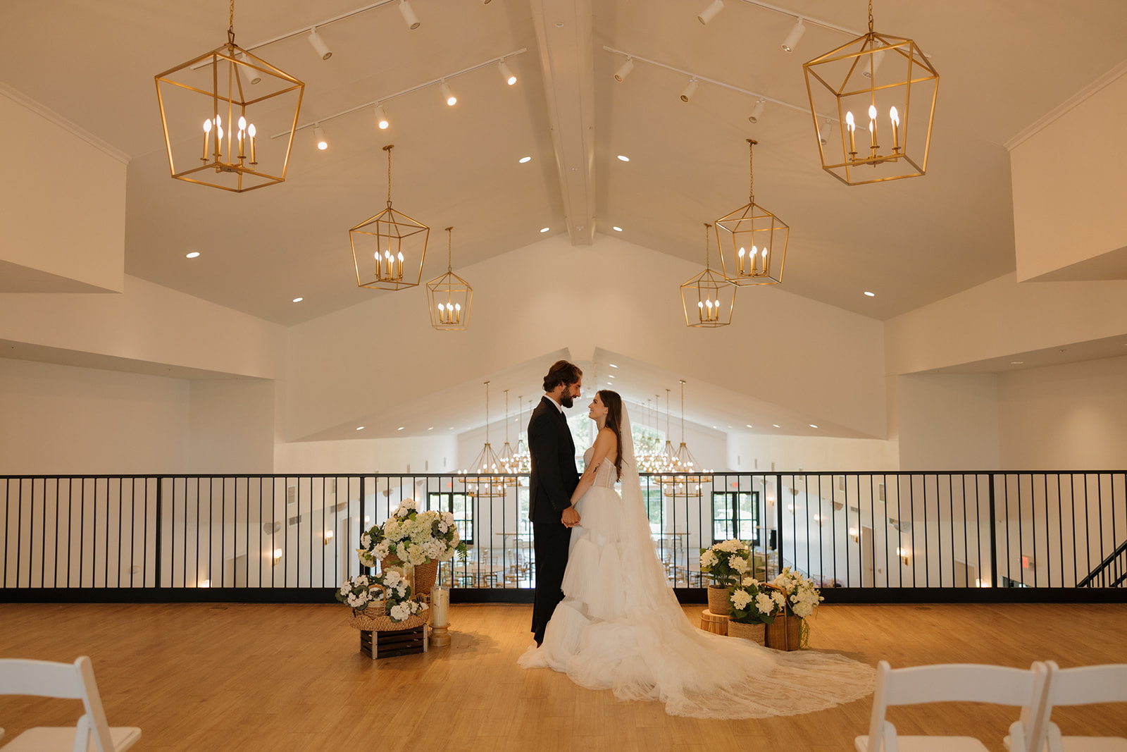 Bride and groom sharing a quiet moment beneath modern gold chandeliers at an airy, light-filled venue—an elegant setting for weddings in Wisconsin.