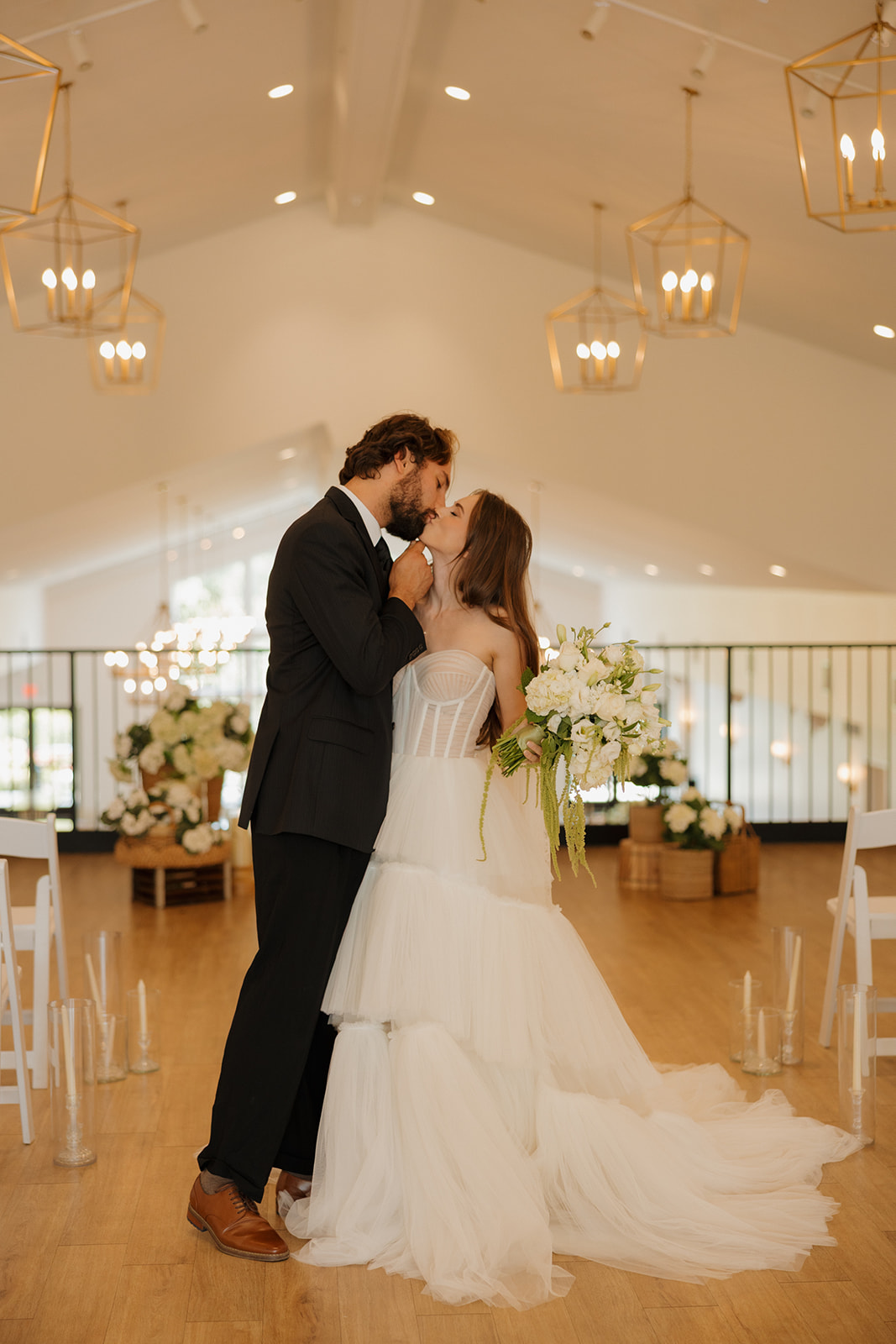 Just-married and just-glowing—bride and groom stroll past blooming flowers and a white building, capturing the charm of weddings in Wisconsin.