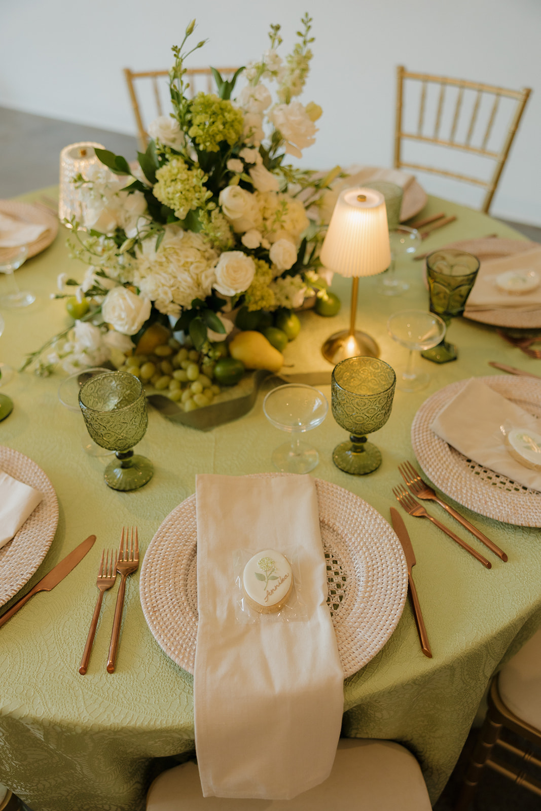 Textured green linen, rattan chargers, and crisp ivory napkins create a layered tablescape full of charm for weddings in Wisconsin.