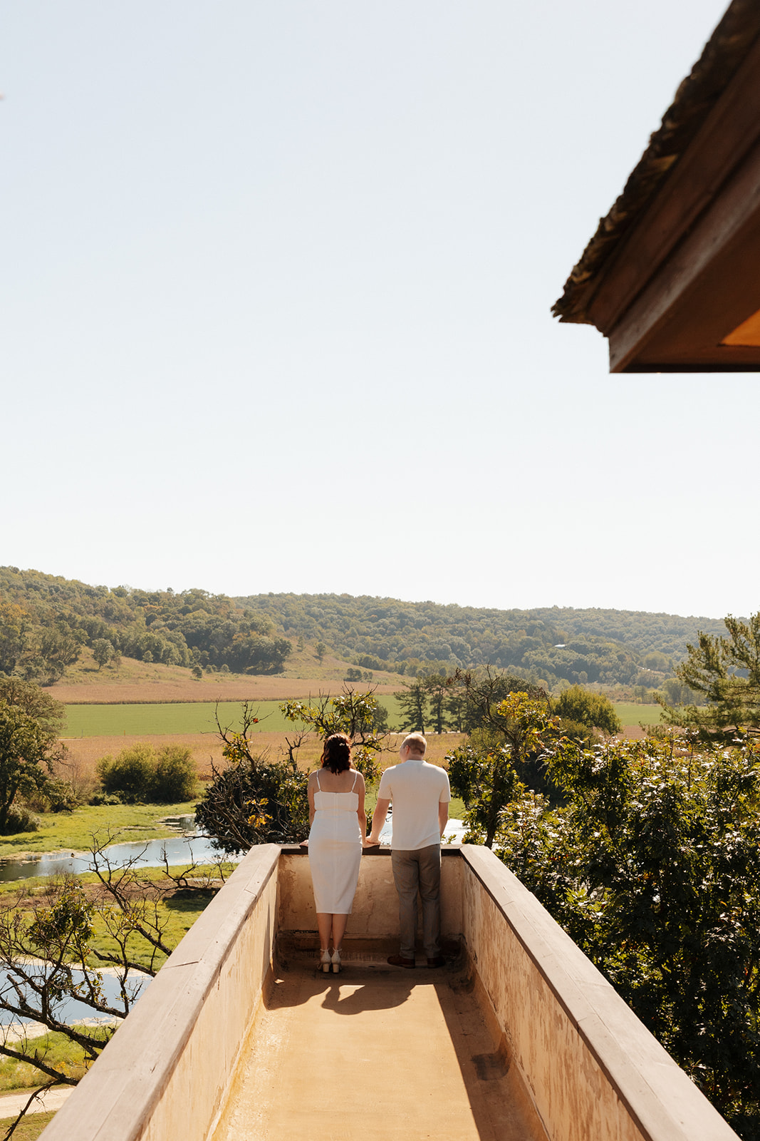 Couple gazing out over a scenic valley from a high, narrow balcony—an intentional and elevated idea for engagement photos that celebrates space and stillness.