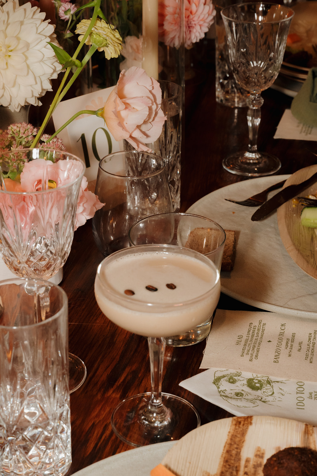 Espresso martini on a candlelit reception table surrounded by pink florals and crystal glassware.