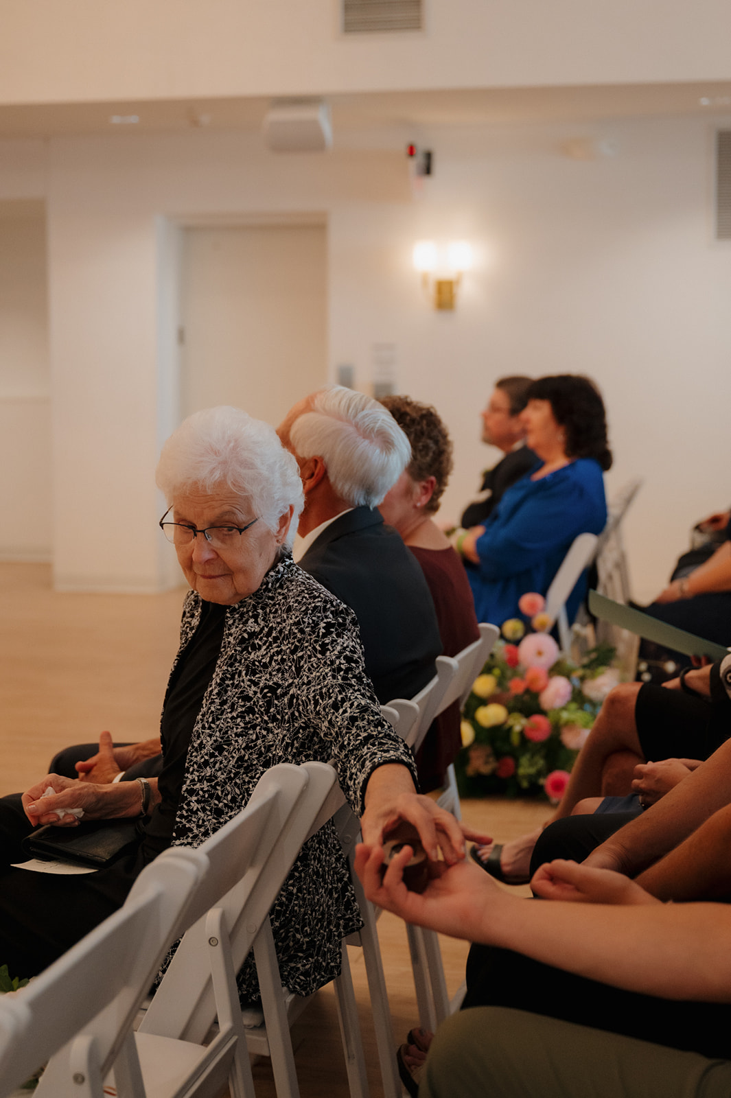 A sweet moment between generations as an elderly guest reaches to hold hands with a loved one during the ceremony.