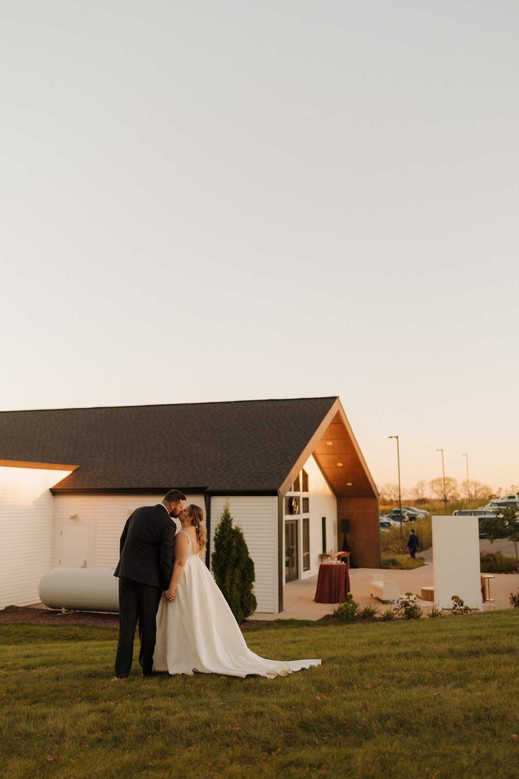 Bride and groom share a quiet moment outside a modern white barn, a wedding venue in Wisconsin glowing in the soft evening light.