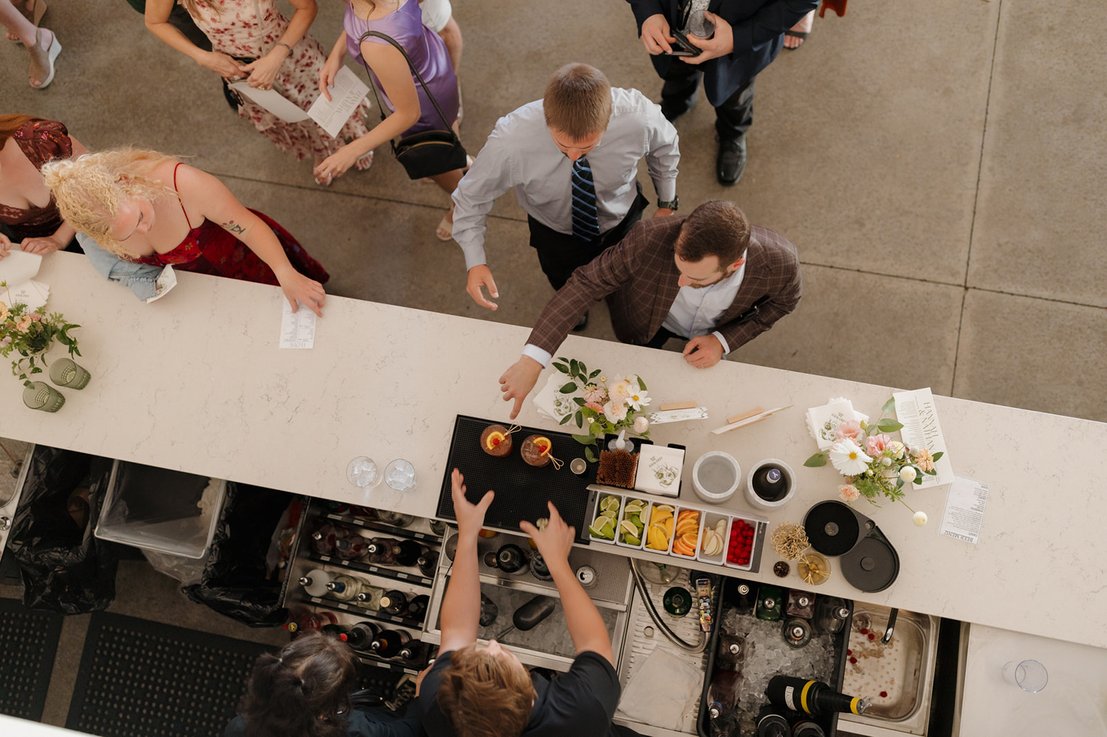 Guests order signature cocktails at a modern bar during a wedding reception.