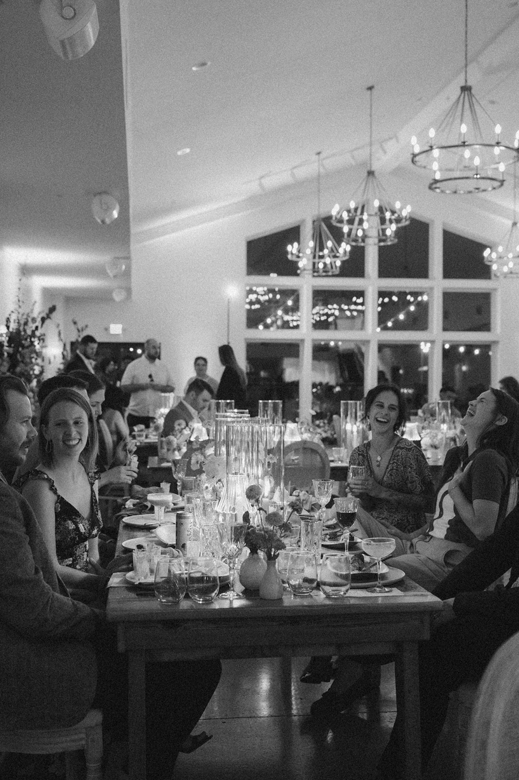Guests laugh and sip cocktails during a candlelit dinner at a modern Wisconsin wedding venue.