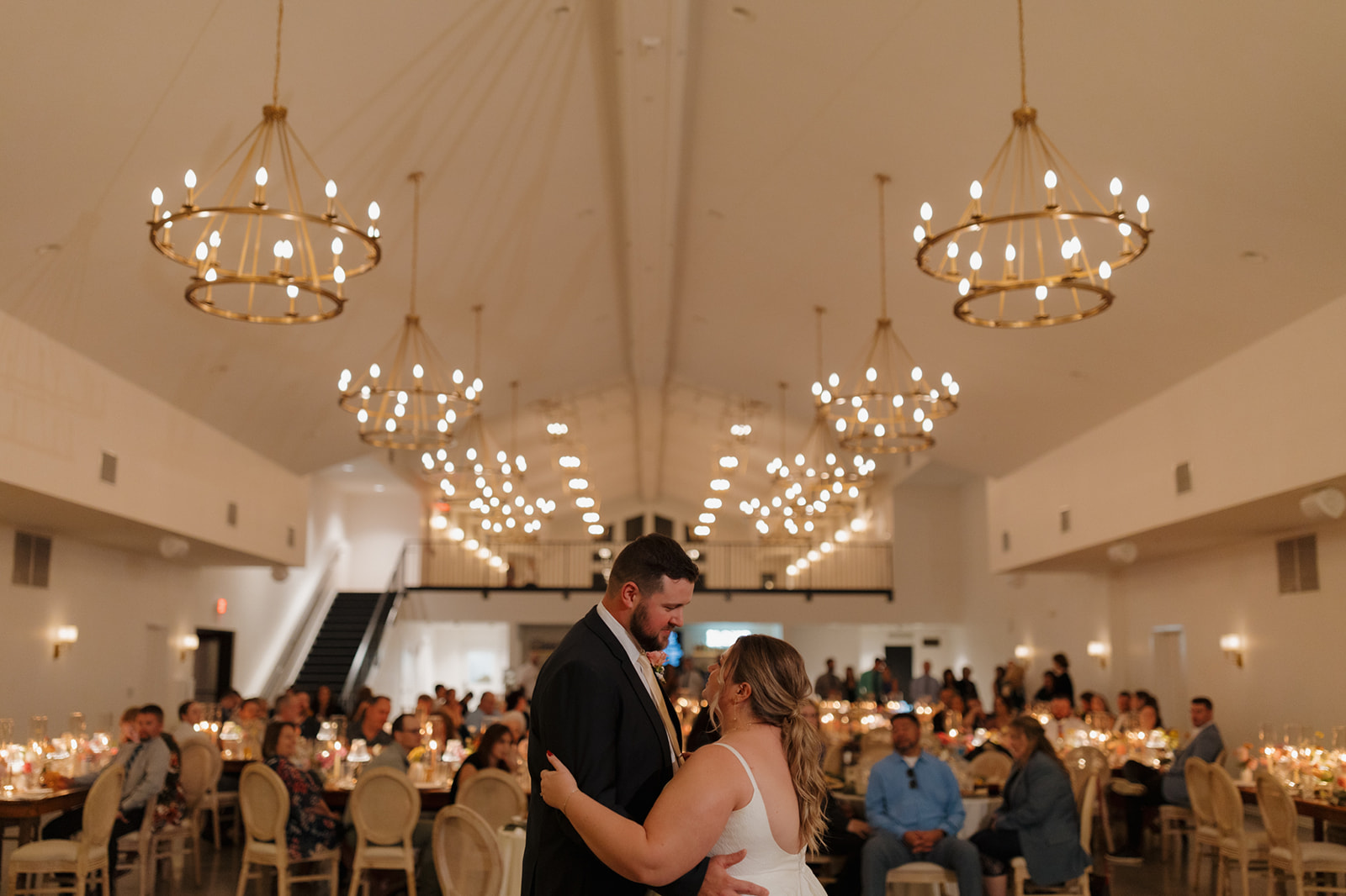 Bride and groom share a first dance under golden chandeliers at their wedding venue in Wisconsin.