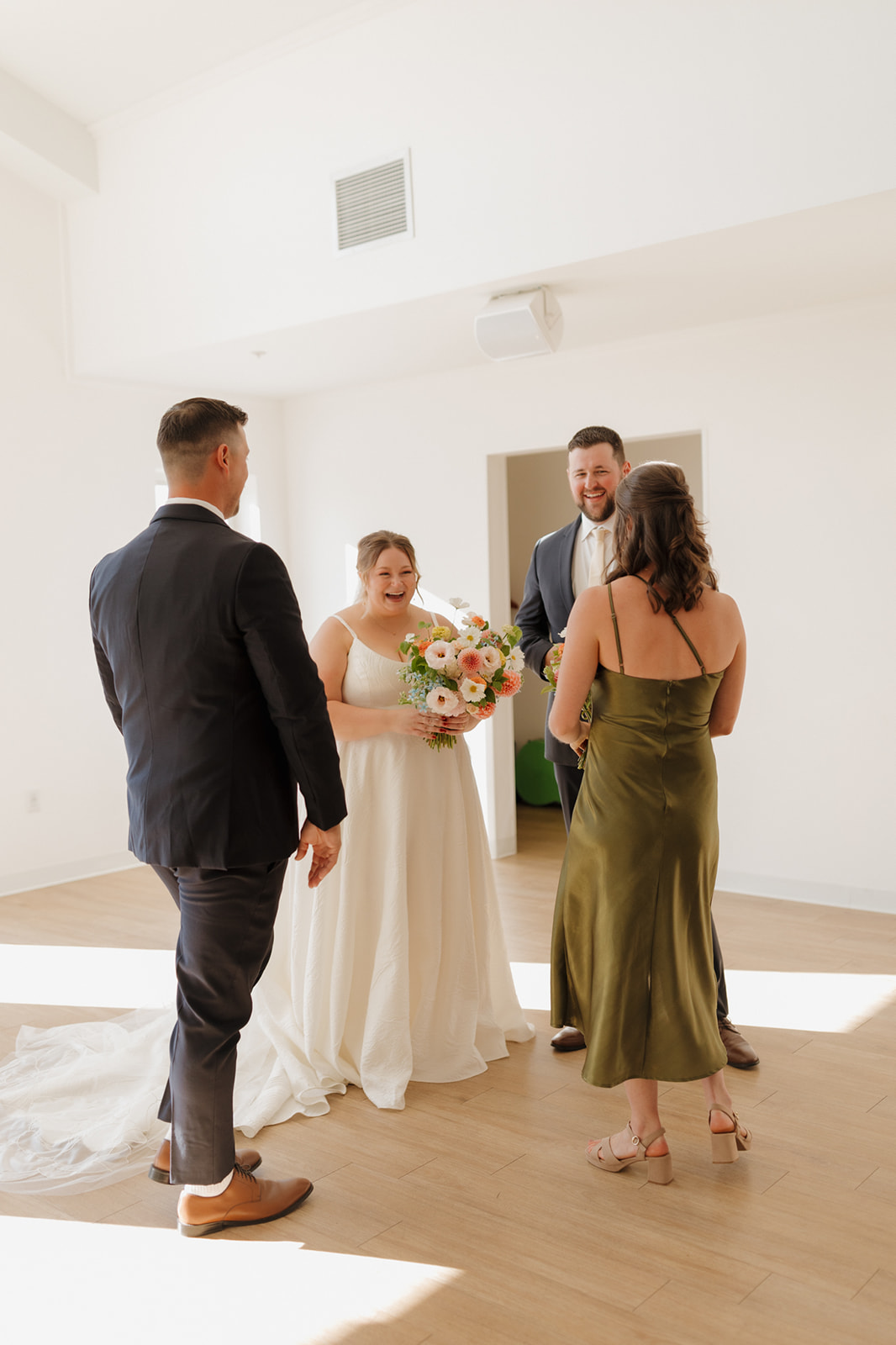 Post-ceremony laughs shared between the couple and their wedding party in a bright, modern space full of natural light.