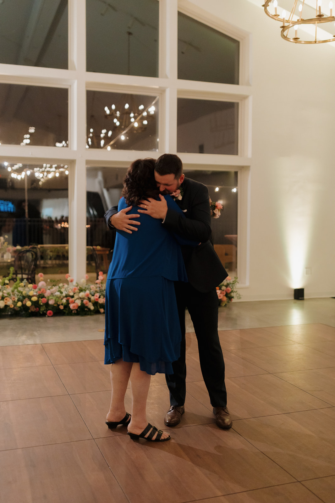Groom hugs his mother during a sweet parent dance inside the reception space.
