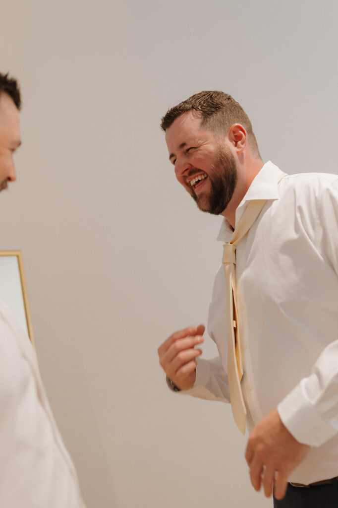 A candid moment full of laughter between the groom and his best man during morning prep.