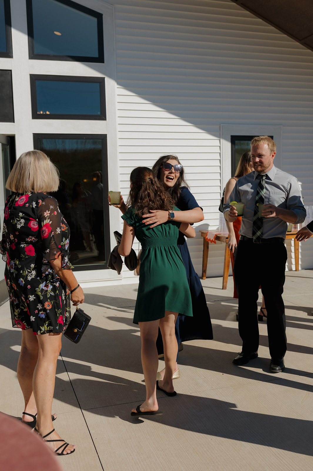 Wedding guests hug and mingle outside the Eloise on a sunny afternoon.