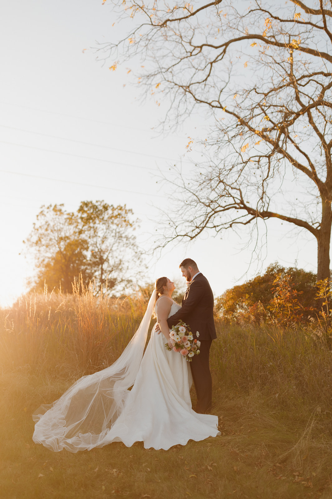 Bride and groom stand together in golden light at their wedding venue in Wisconsin.