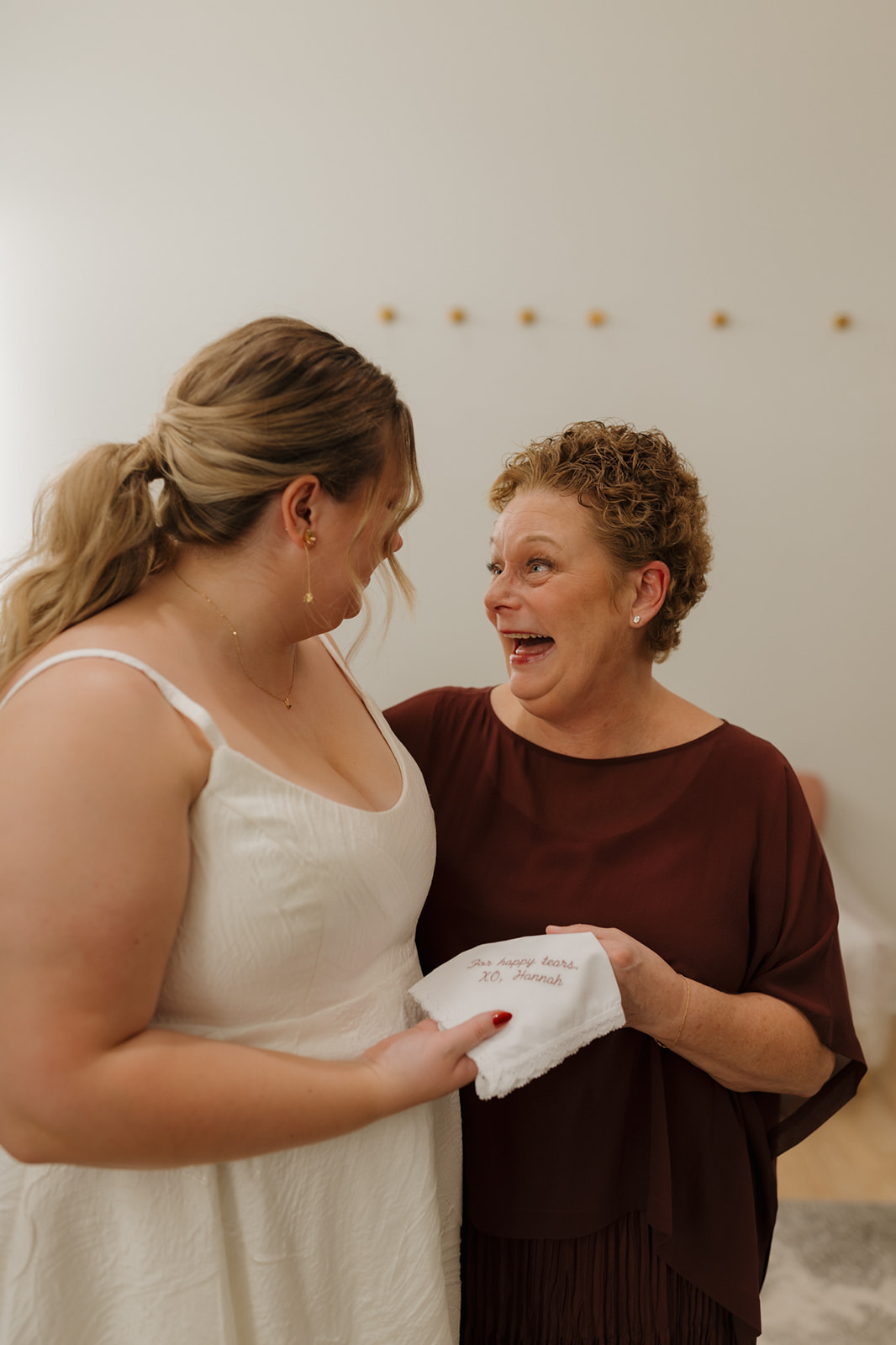 Bride and her mom sharing an emotional exchange over a personalized handkerchief before the ceremony.