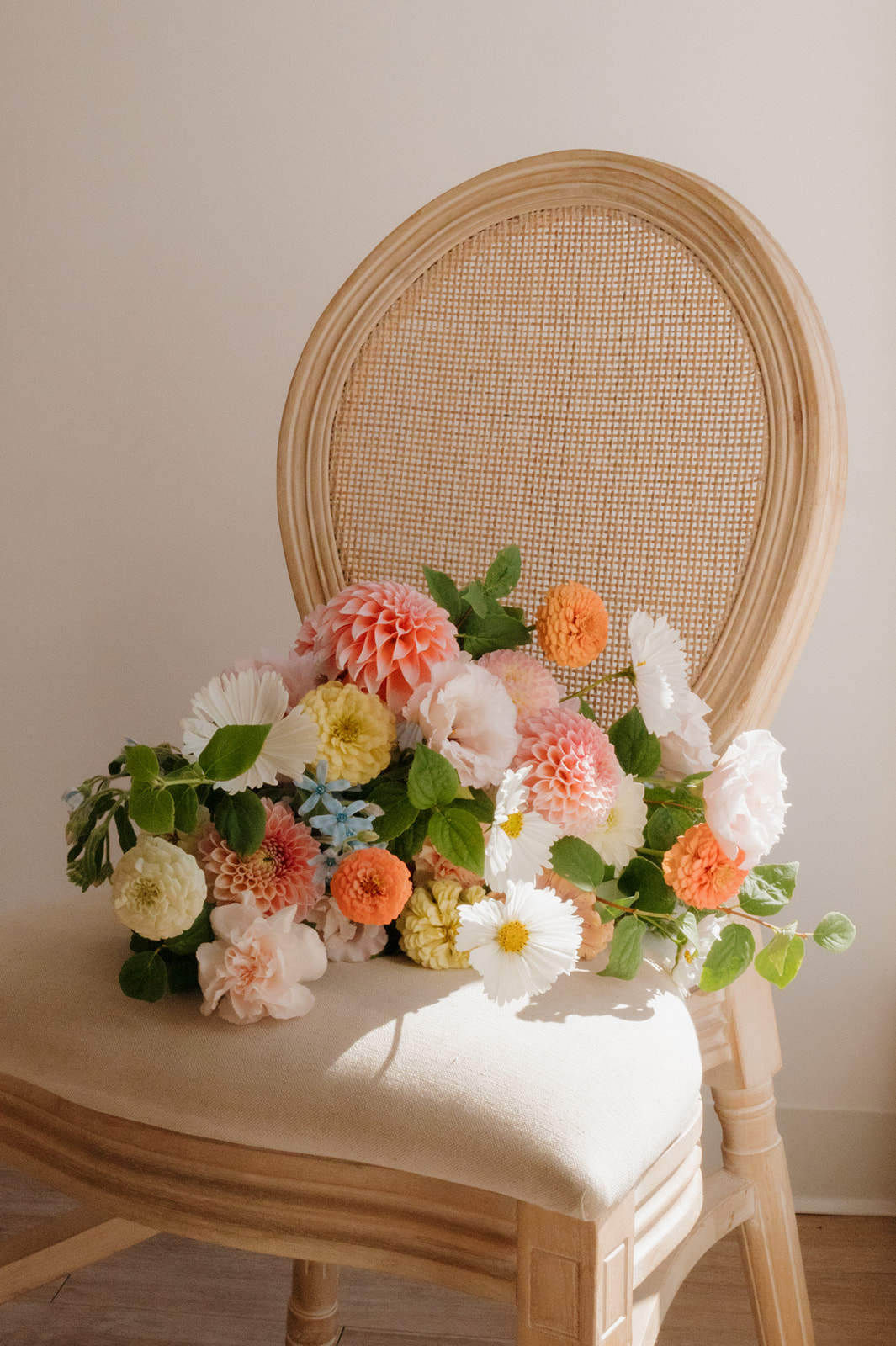 Close-up of a romantic bridal bouquet full of dahlias, zinnias, and garden roses in soft and bold tones.