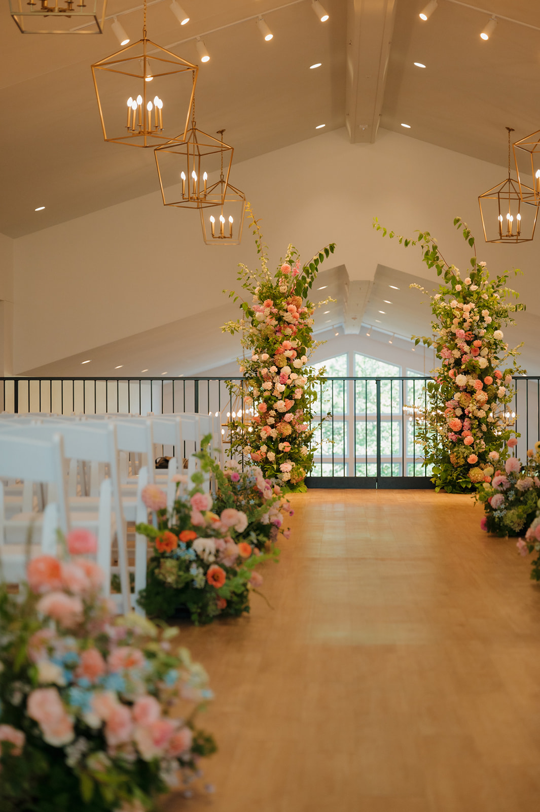 Floral-lined ceremony aisle with two lush arrangements framing the altar inside a modern wedding venue in Wisconsin.