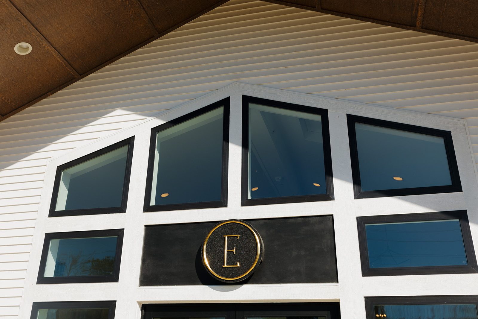 Exterior of a stylish black and white barn with a bold “E” emblem, showcasing a contemporary wedding venue in Wisconsin.