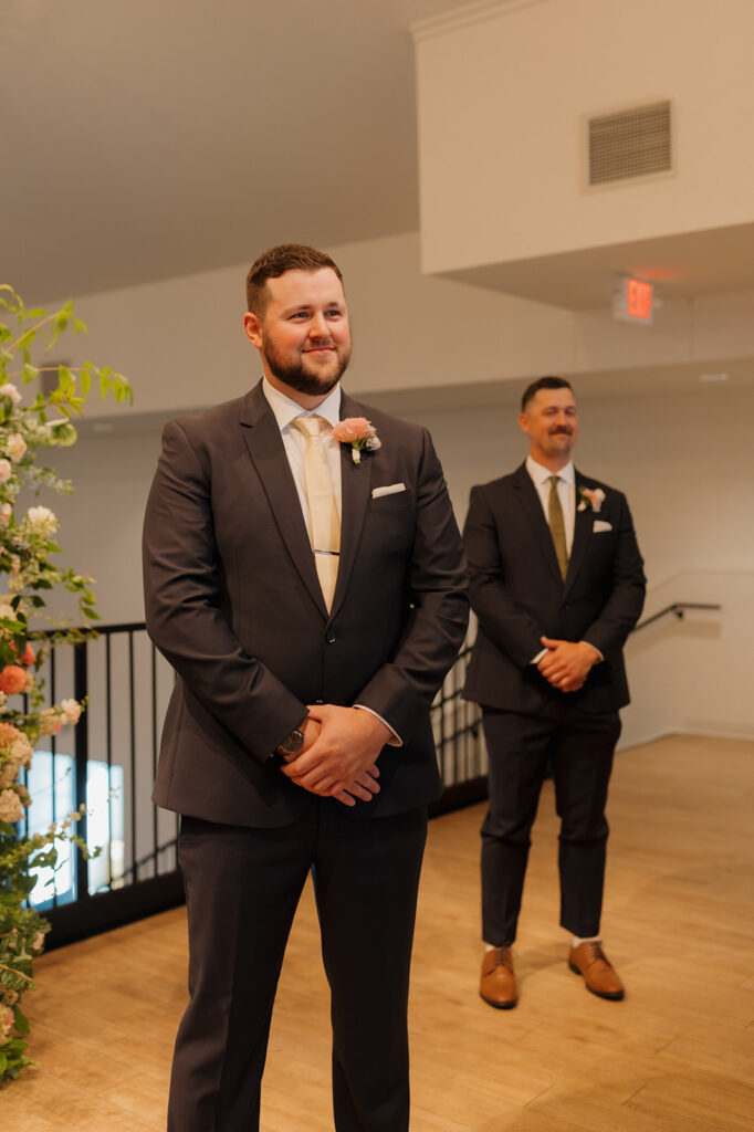 Groom waiting at the altar with his best man, surrounded by florals and modern touches at a wedding venue in Wisconsin.