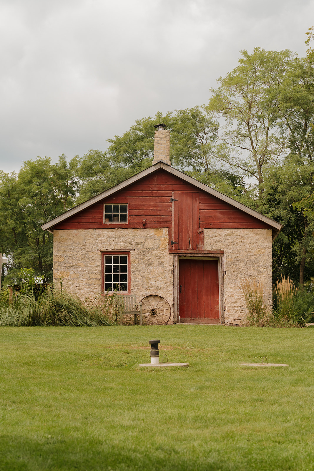 A charming stone outbuilding with a red wooden top, nestled among trees—just one example of character-filled spaces at Madison wedding venues.