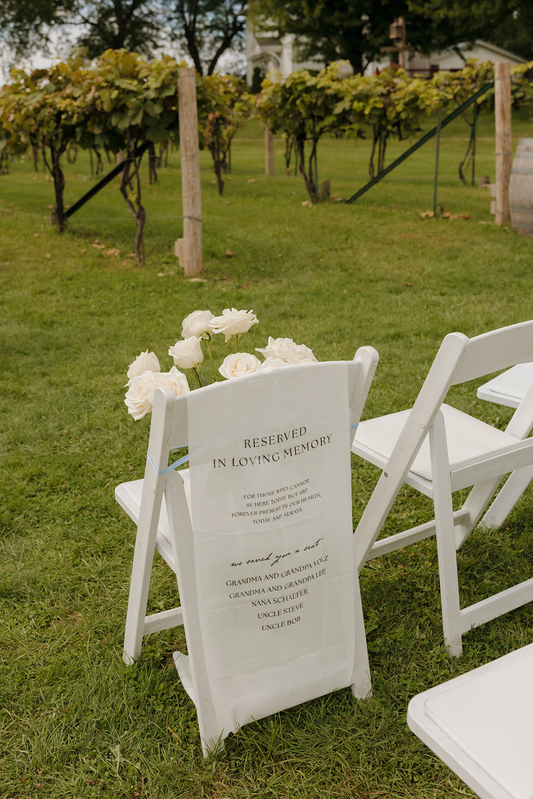 A touching tribute at the ceremony—white chair marked “In Loving Memory” with roses and a custom printed seat cover.