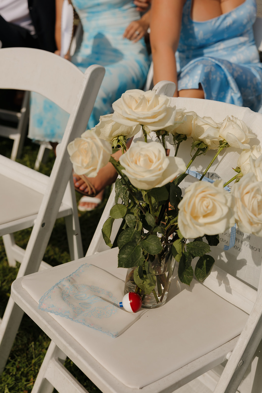 Simple and sweet: a mason jar of white roses and a delicate handkerchief placed on a chair for ceremony guests.