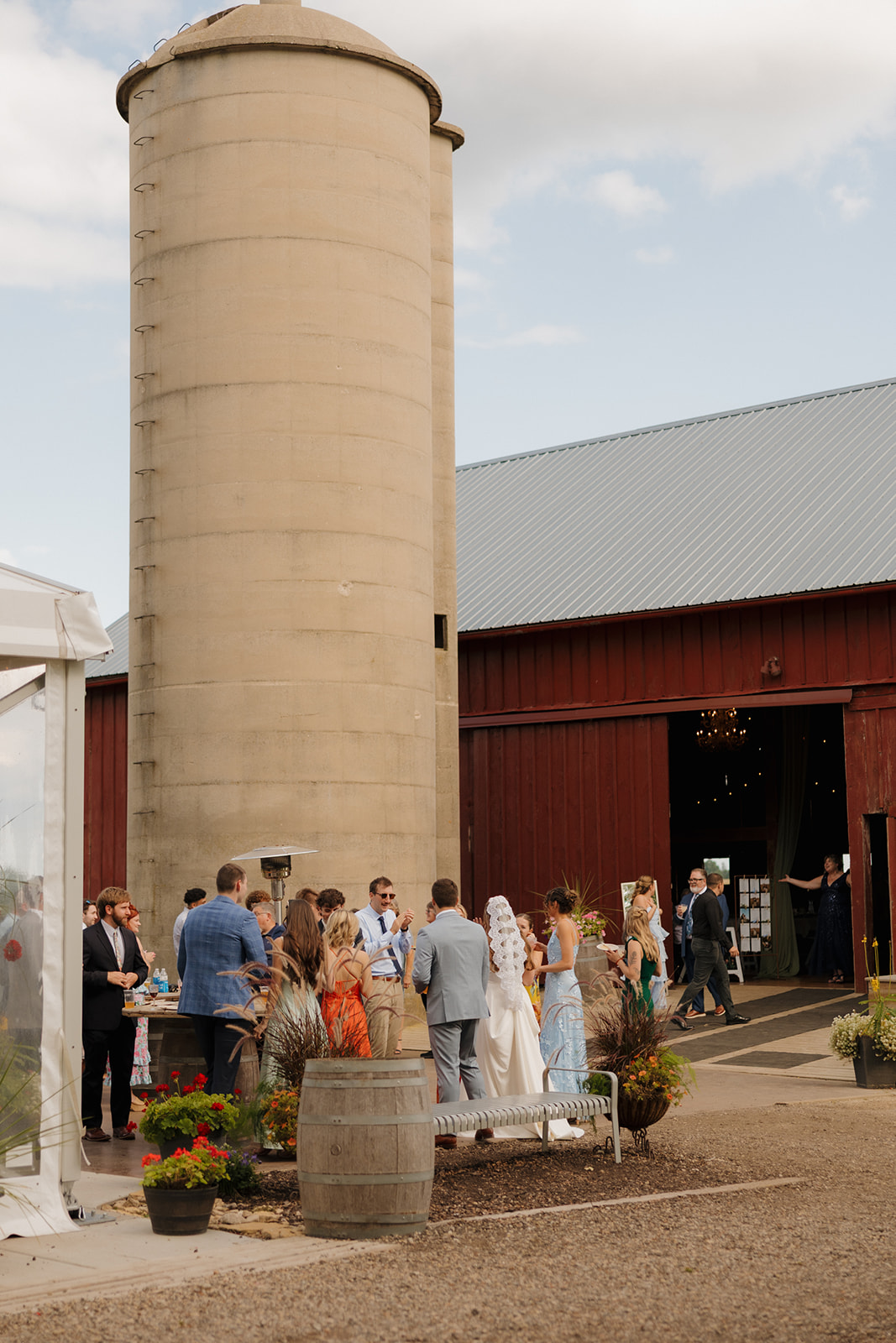 Guests gather around the barn and silo, sipping drinks and soaking in the cozy charm of one of the most beloved Madison wedding venues.