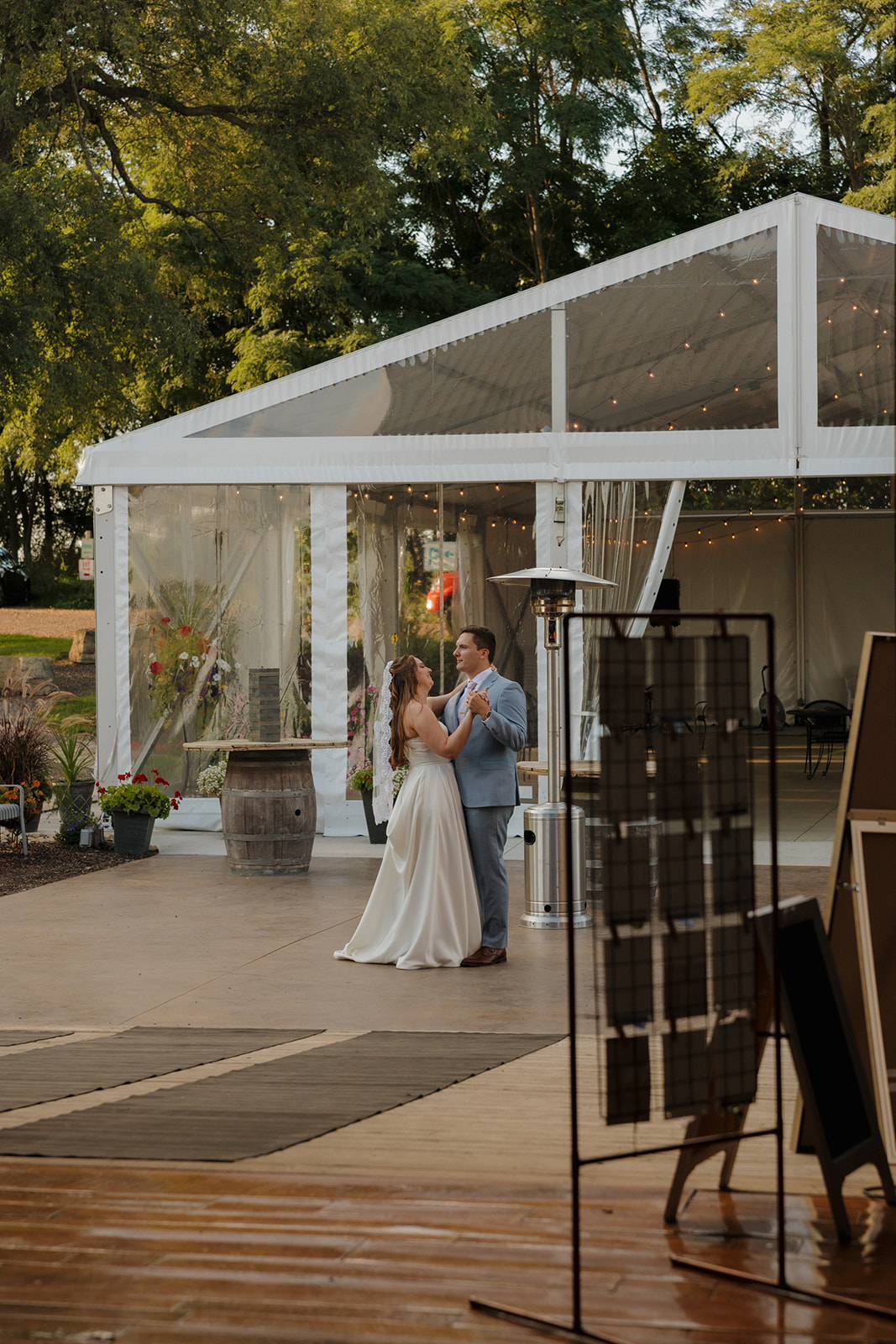Golden hour glow surrounds the couple during their first dance just outside a sparkling clear tent.