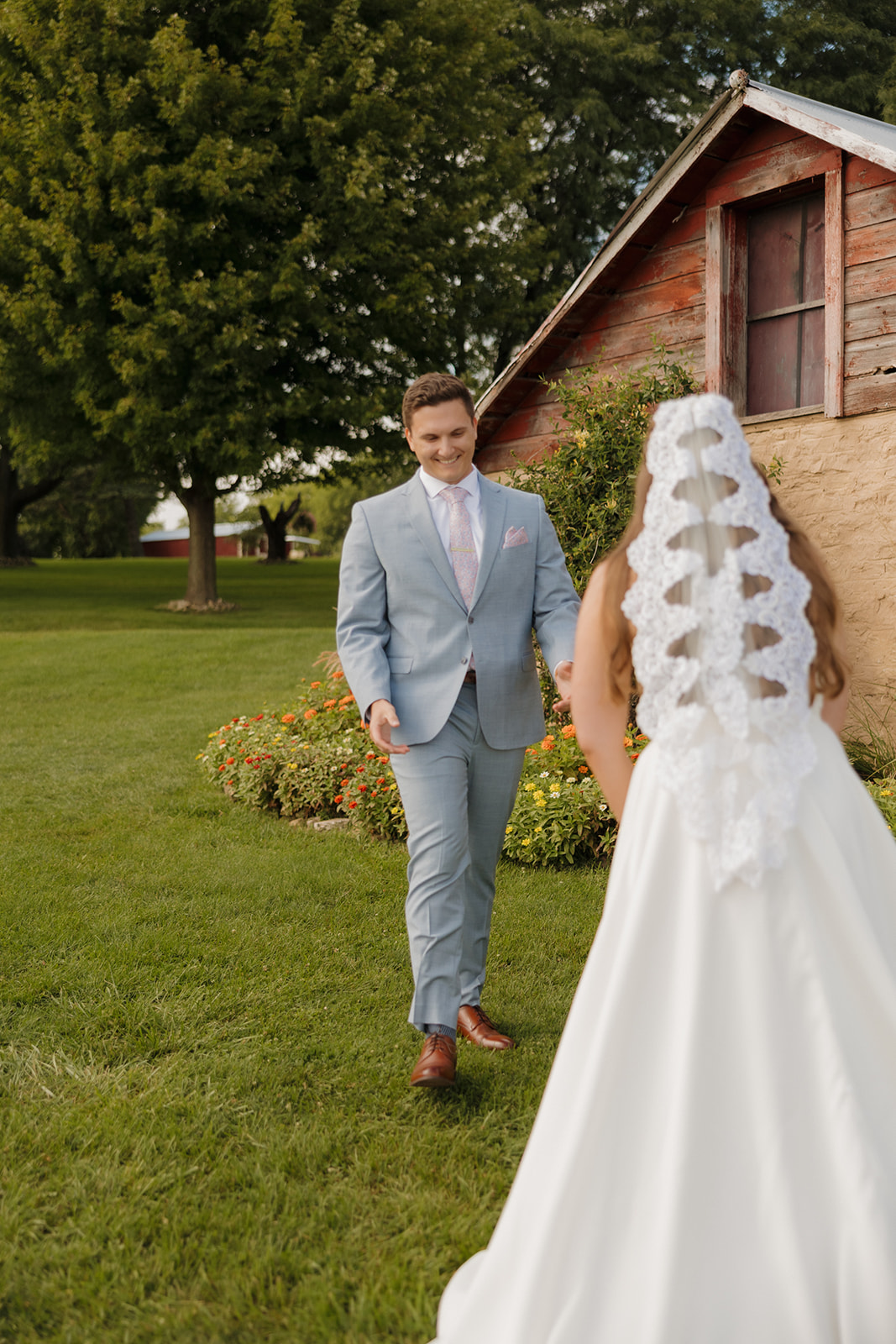 The groom’s joyful reaction as he sees his bride for the first time, set against the rustic charm of a Madison wedding venue.