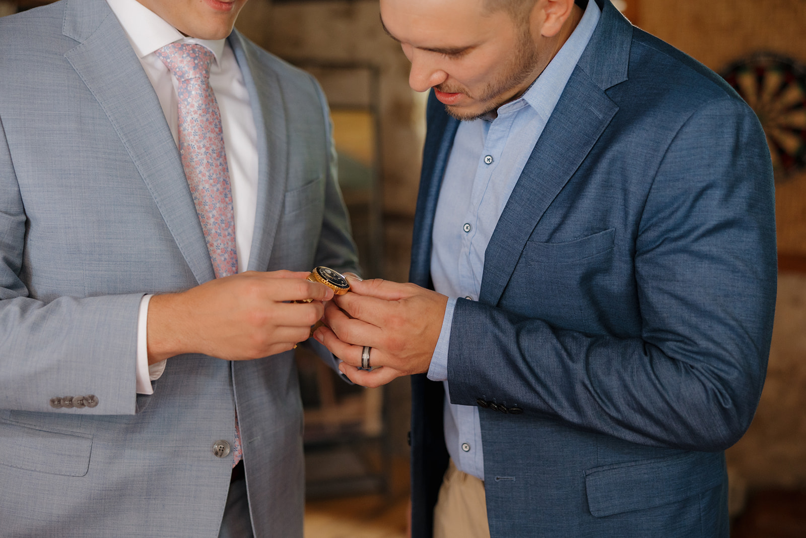 The groom shares a meaningful watch with his best man, suited up in soft blue jackets with a hint of nerves and nostalgia.