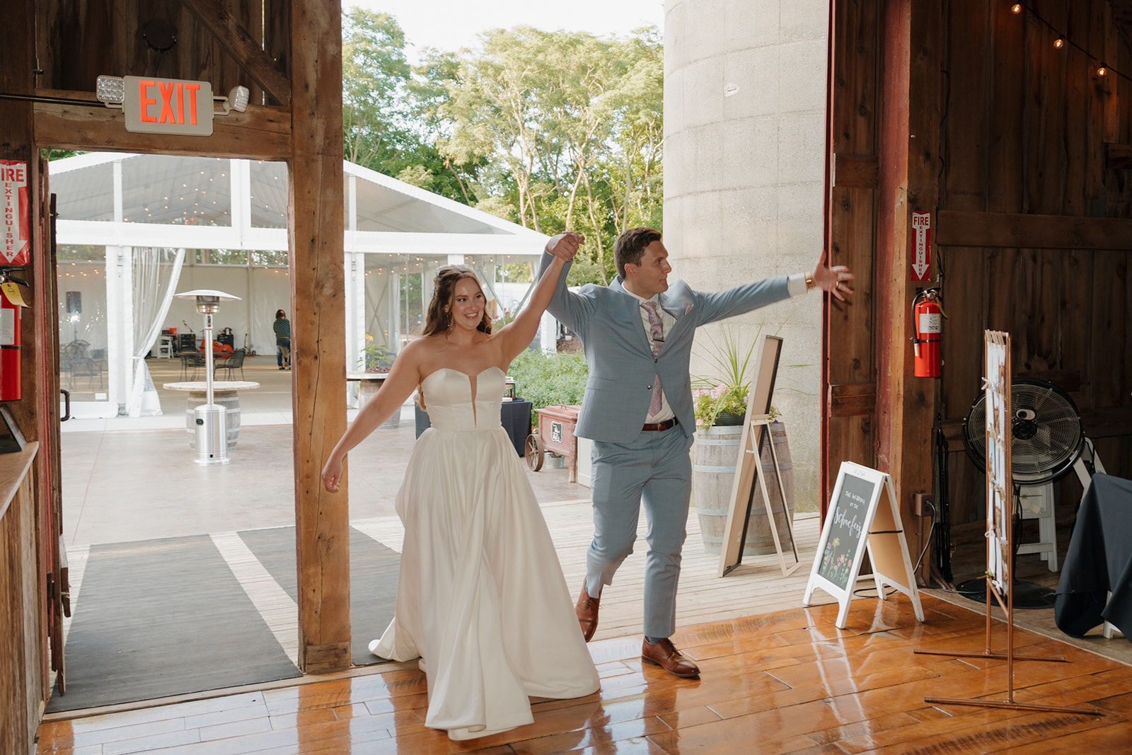 The couple makes a grand entrance into the reception, hands raised, all smiles, and ready to party.