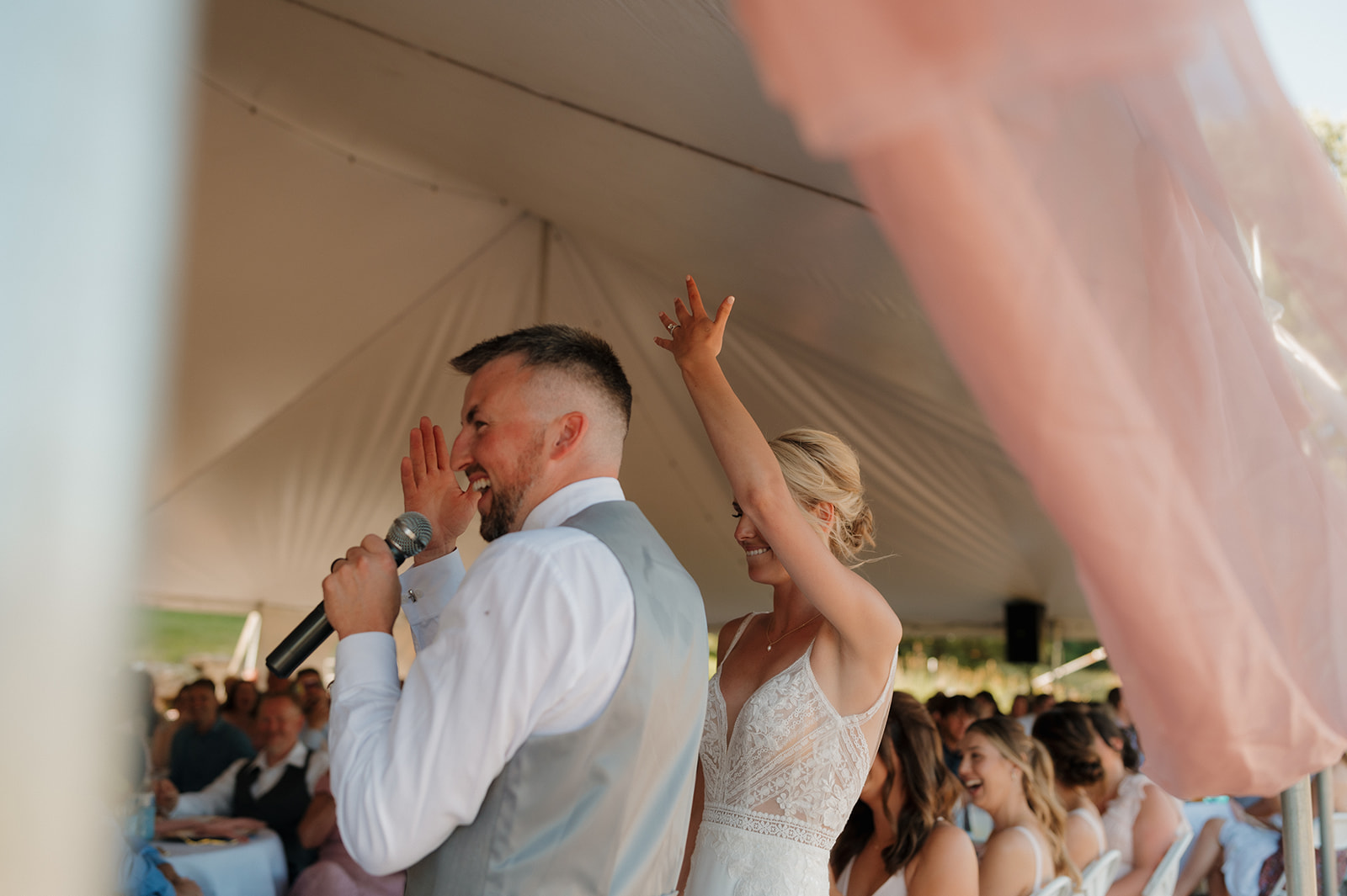 Bride and groom raise their arms in celebration under a floral arbor at their Wisconsin winery wedding venue.