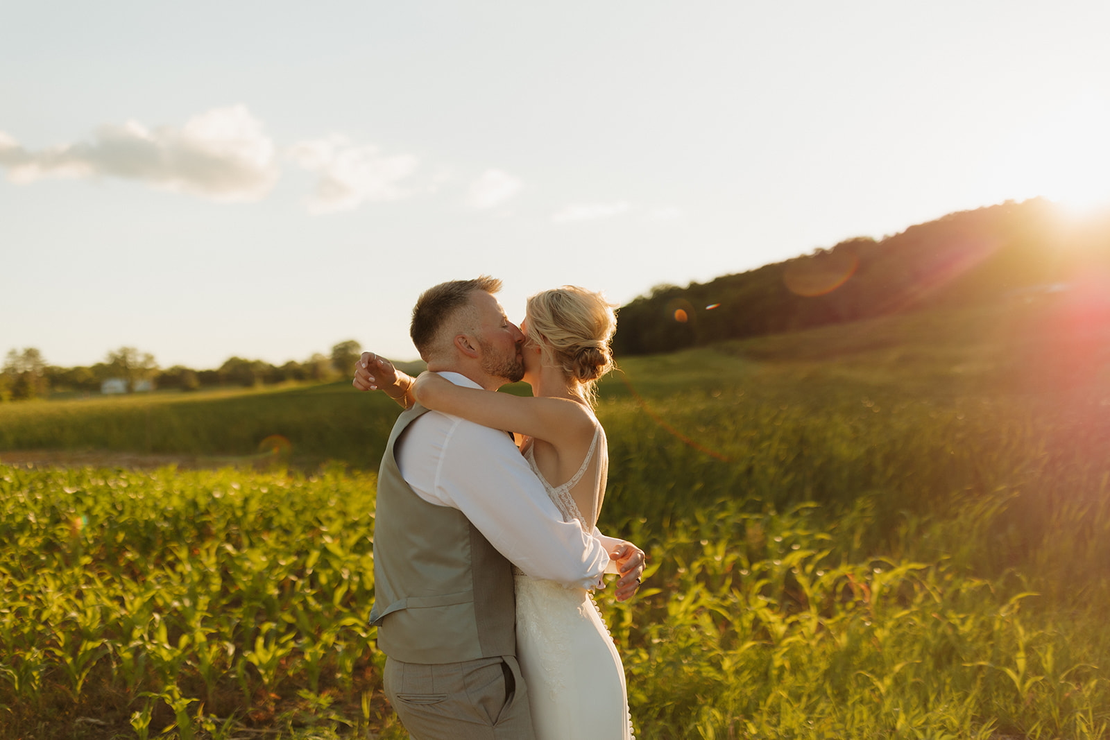 Bride and groom share a golden hour kiss surrounded by open fields at a Wisconsin winery wedding venue.