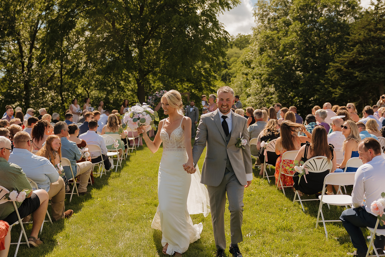 Beaming newlyweds walk hand in hand after saying “I do” at their Wisconsin winery wedding venue.