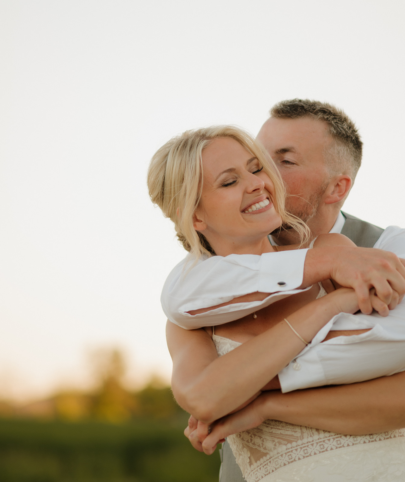 Bride laughing as groom wraps her in a joyful post-ceremony embrace.