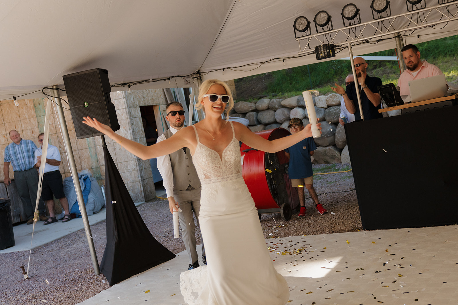 Bride enters the dance floor wearing sunglasses and holding confetti poppers, ready to celebrate.