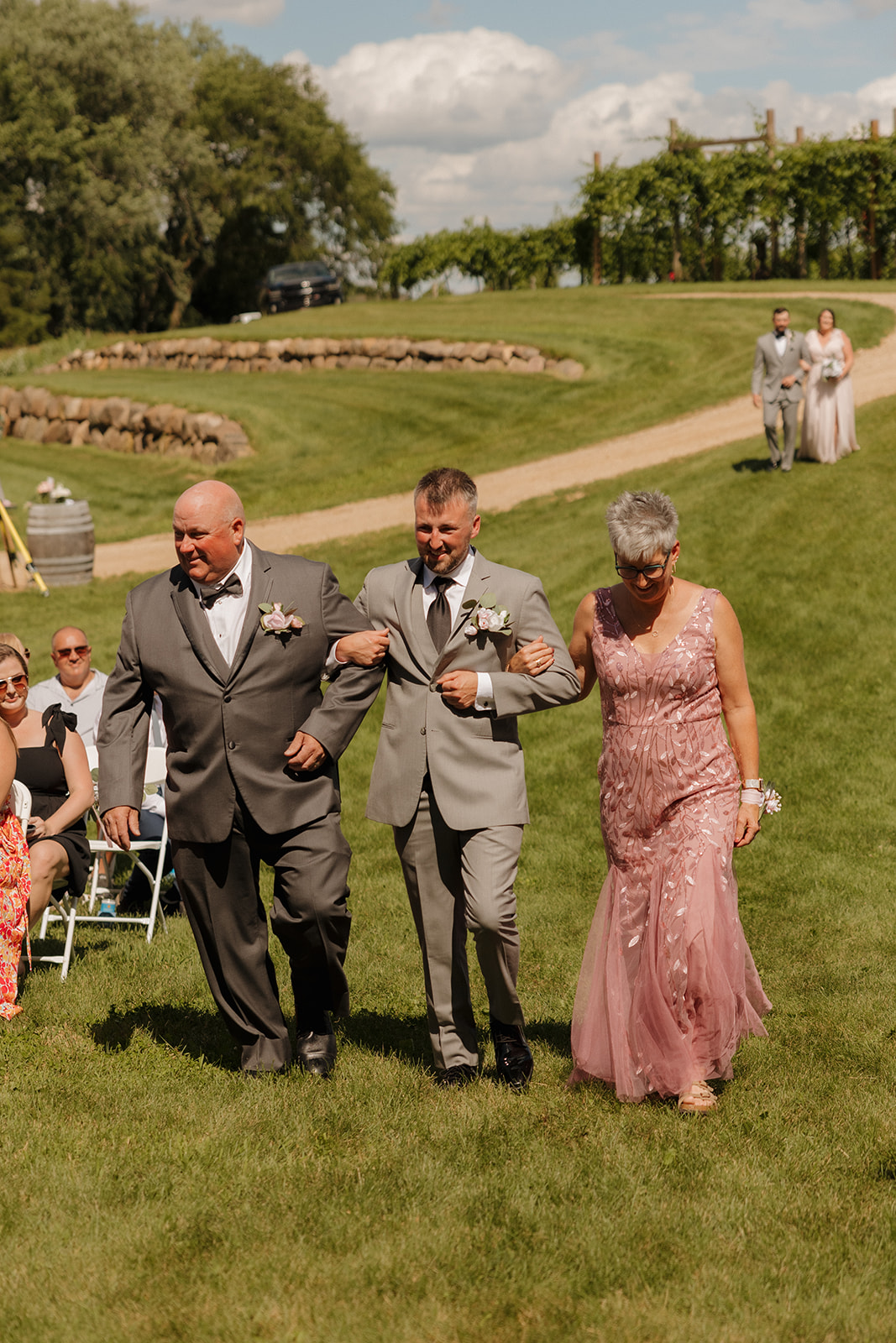 Groom escorted by his parents down the aisle at a winery wedding ceremony in Wisconsin.