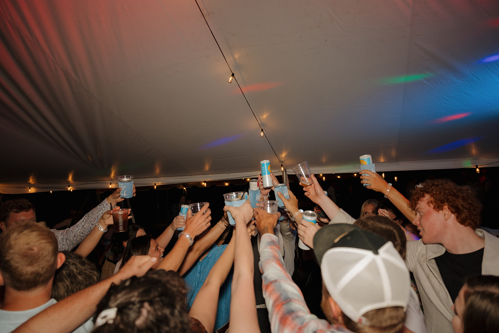 Wedding guests raise their drinks in celebration under the stars.