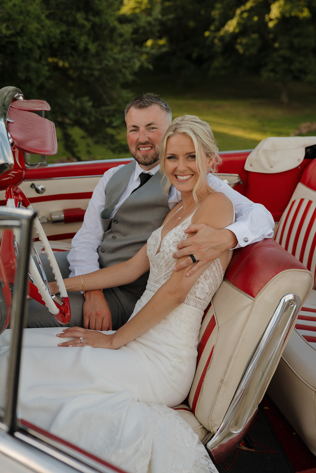 Just-married couple posing in a vintage red convertible at their Wisconsin winery wedding.
