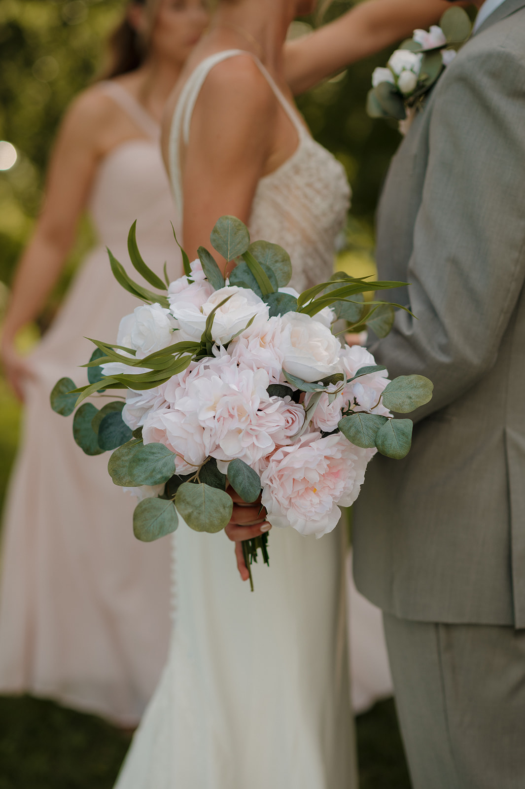 Close-up of the bride’s bouquet filled with pale pink peonies and eucalyptus leaves.