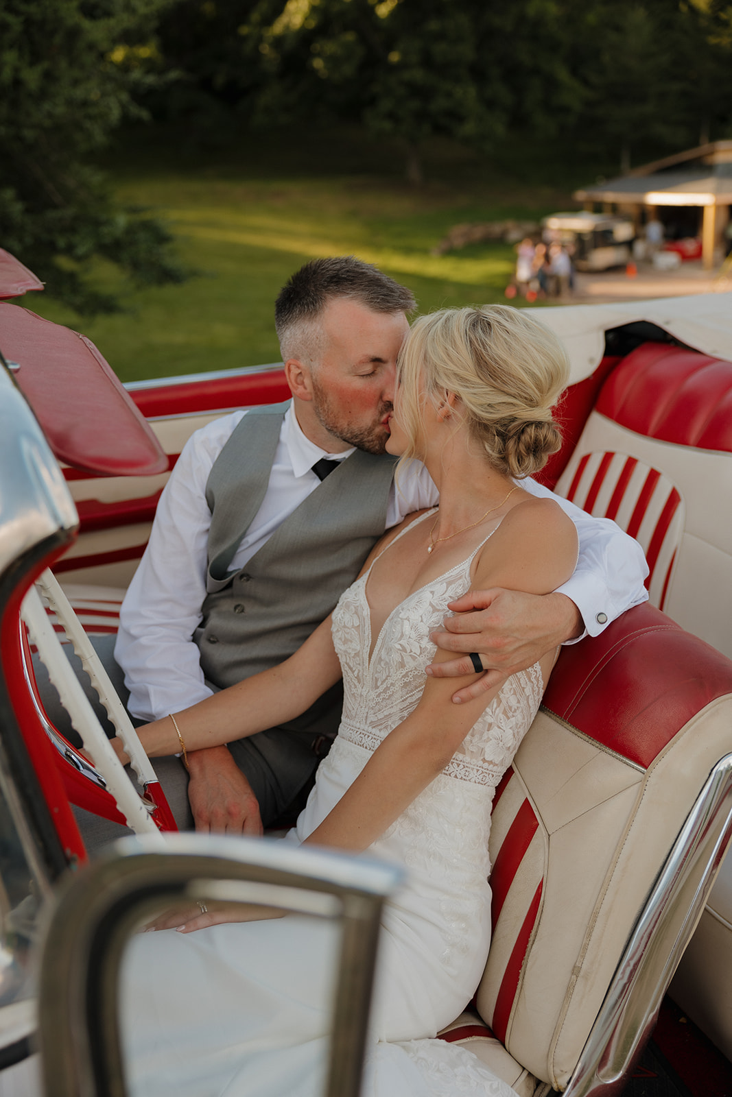 Couple shares a romantic kiss in a vintage red-and-white convertible.