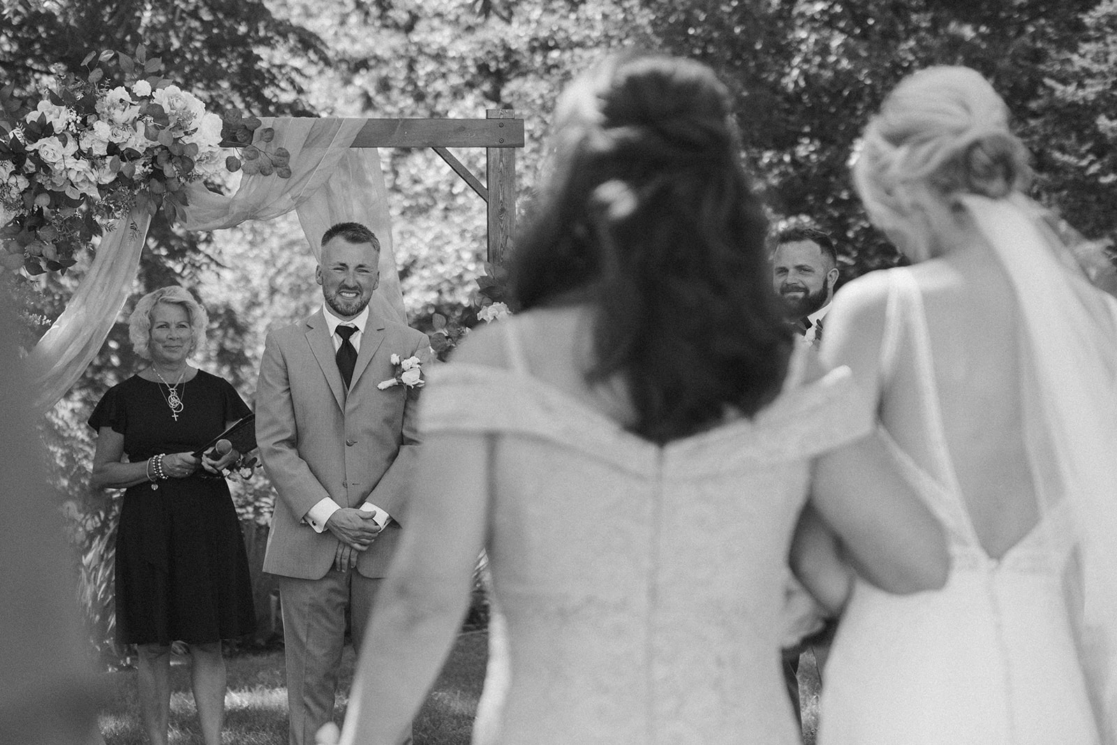Groom smiling emotionally as he sees the bride approach at a Wisconsin winery wedding ceremony.