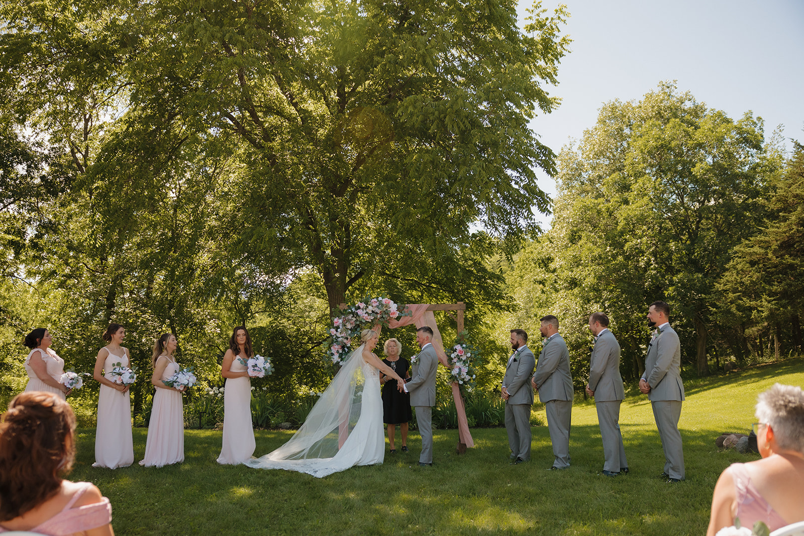 Bride and groom exchange vows beneath a floral arch at a scenic Wisconsin wedding venue.