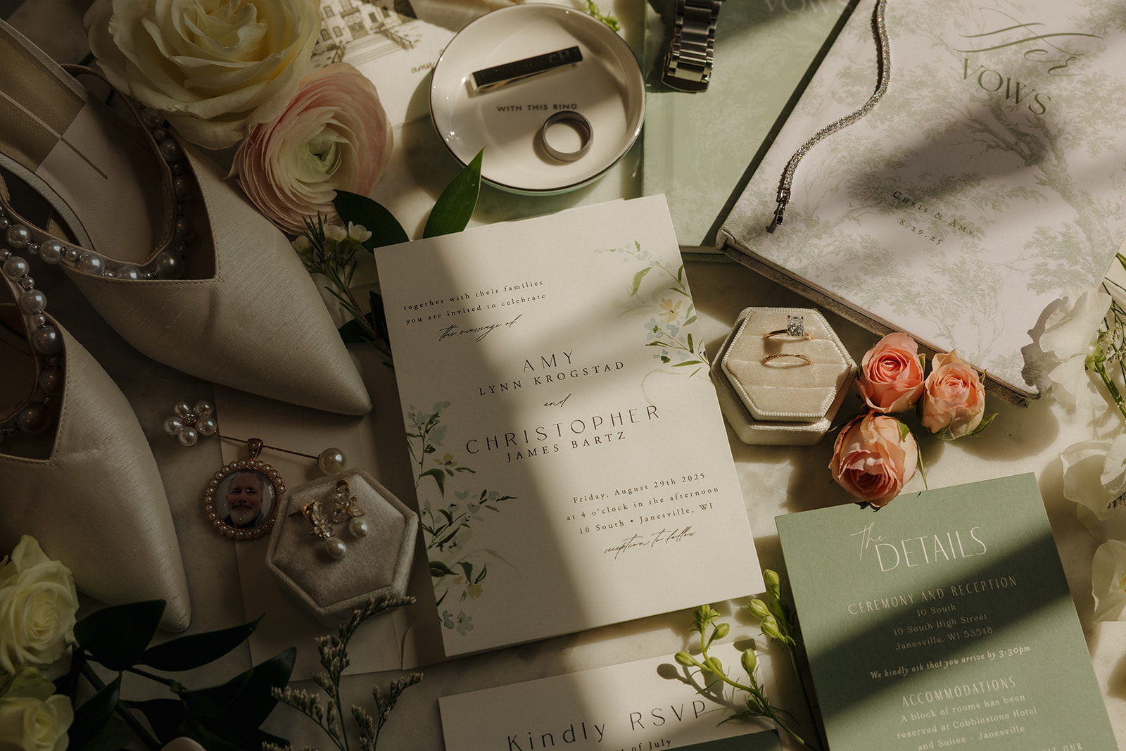 A romantic flat lay of wedding day details: invitation suite, vow book, rings, shoes, florals, and sentimental heirlooms—an elegant moment documented by wedding photographers in Wisconsin.