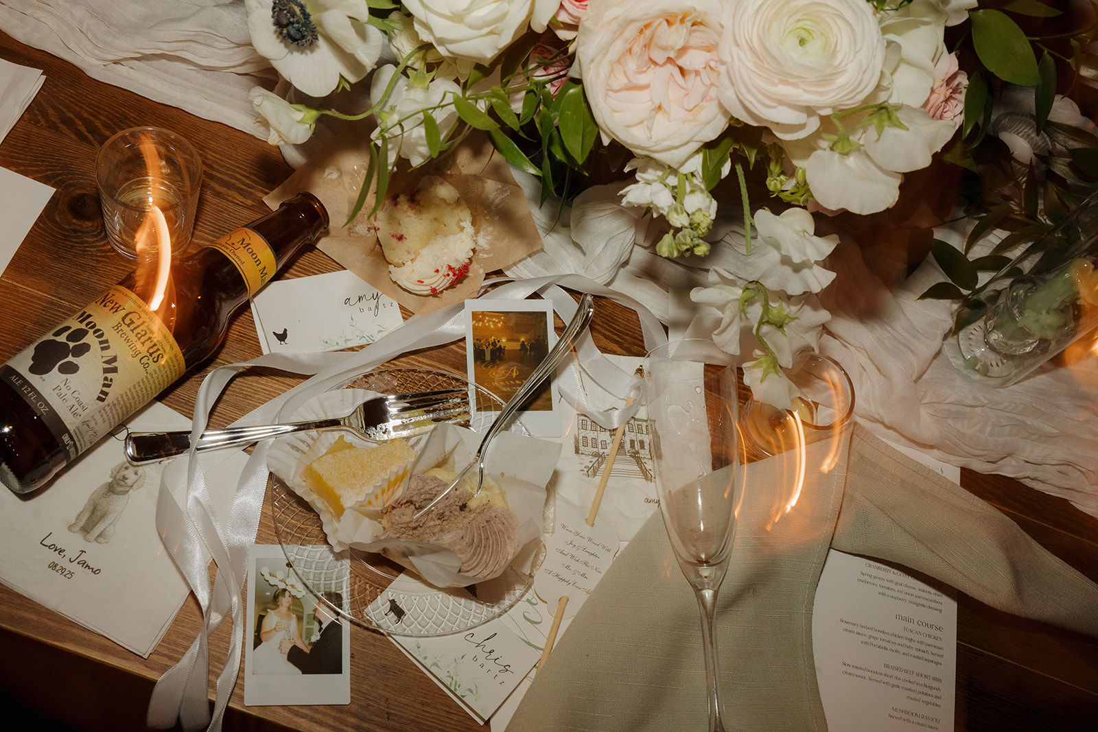 An artfully messy flat lay of desserts, Moon Man beer, florals, and Polaroids captures the joyful chaos of a night well-lived.