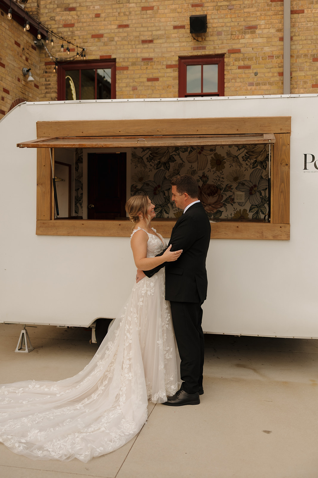 The bride and groom share a quiet moment in front of a vintage mobile bar, captured beautifully by wedding photographers in Wisconsin.
