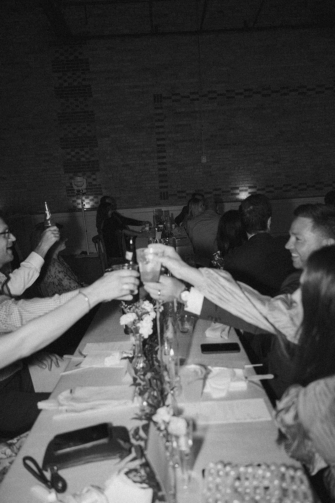 In a blur of laughter and clinking glasses, guests toast the couple during a lively reception dinner.