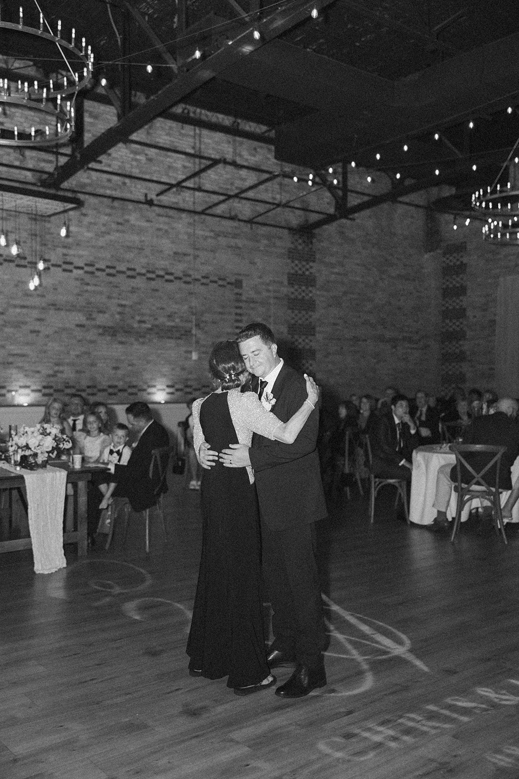 The groom shares a heartfelt dance with his mom under romantic string lights—an emotional moment captured by wedding photographers in Wisconsin.