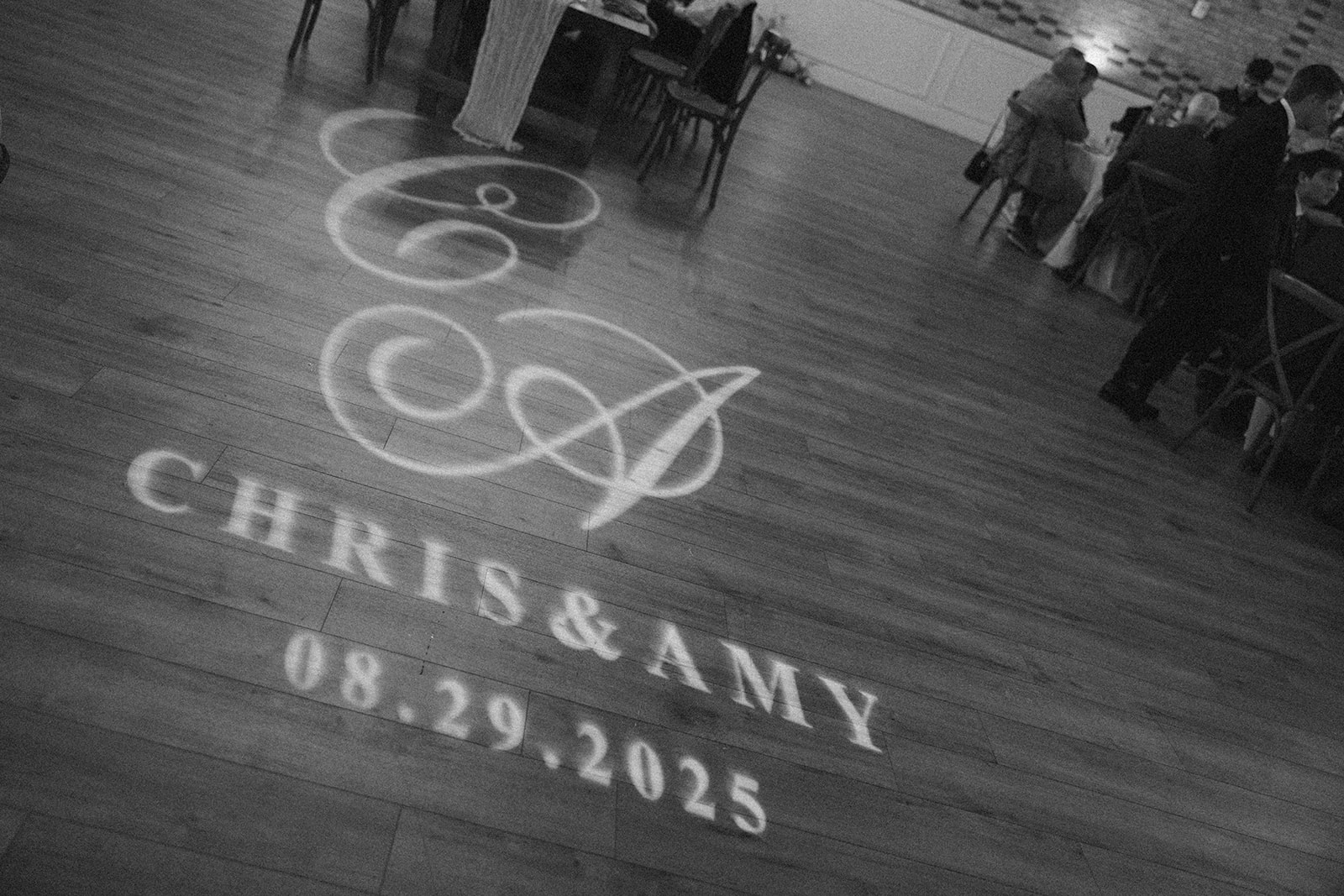 A monogram spotlight on the wood dance floor reads “Chris & Amy 08.29.2025”—a timeless touch at their celebration.