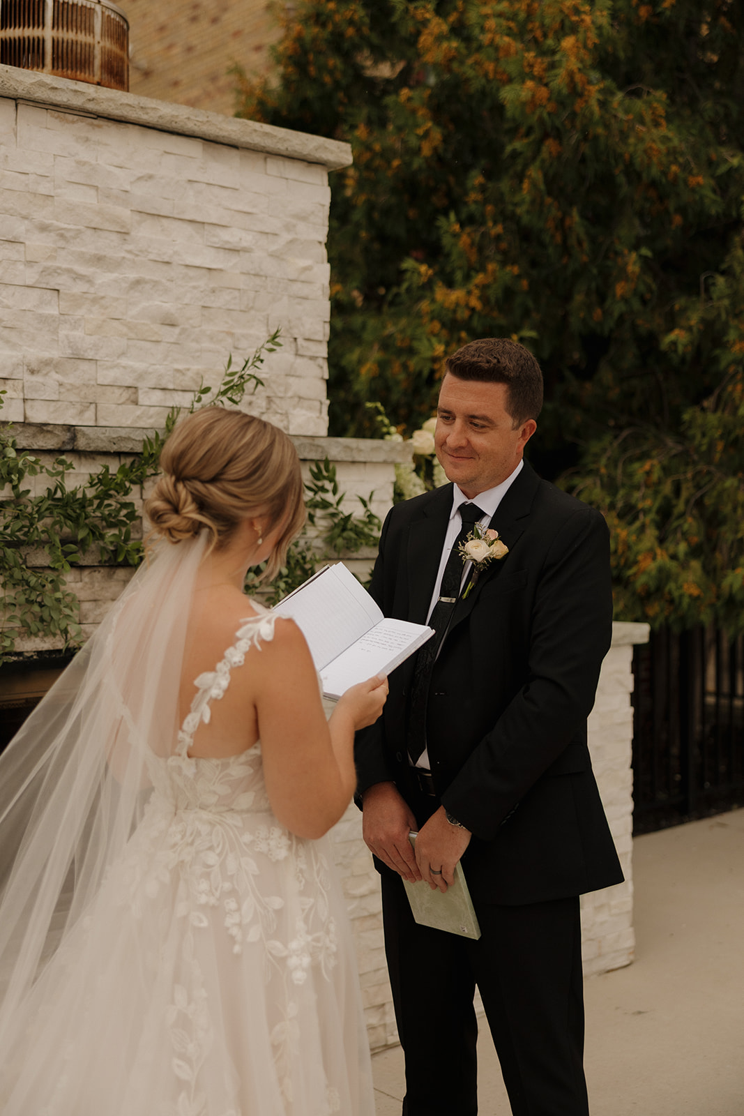The bride reads from a handwritten vow journal while the groom looks on lovingly—an emotional moment wedding photographers in Wisconsin live for.