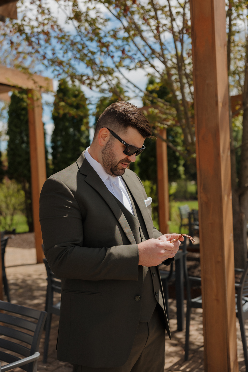 Groom adjusting his sunglasses outdoors at Boxed and Burlap Delavan before the ceremony begins.