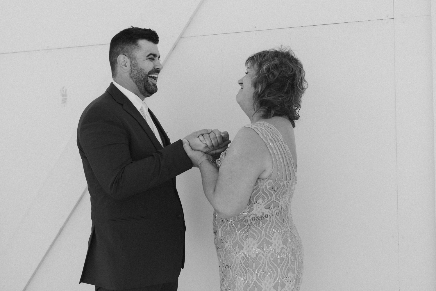 Black and white photo of the groom and his mother laughing together during a quiet moment before the ceremony.
