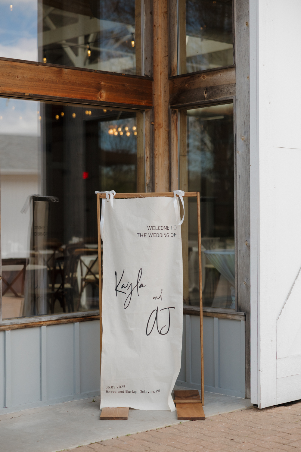 Wedding welcome sign displayed outside Boxed and Burlap Delavan featuring the couple’s names and wedding date.